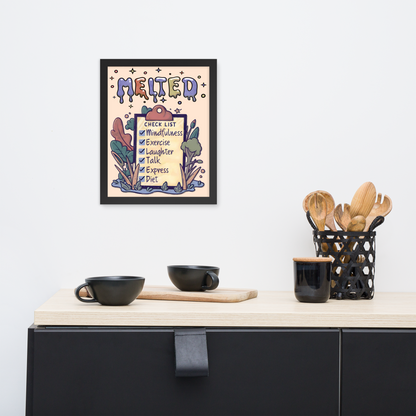 Framed illustrated poster with a black frame titled 'MELTED' featuring a checklist with items: Mindfulness, Exercise, Laughter, Talk, Express, Diet. The poster is hanging on a white wall above a minimalist kitchen counter with black cups, a wooden cutting board, and a black utensil holder with wooden utensils.