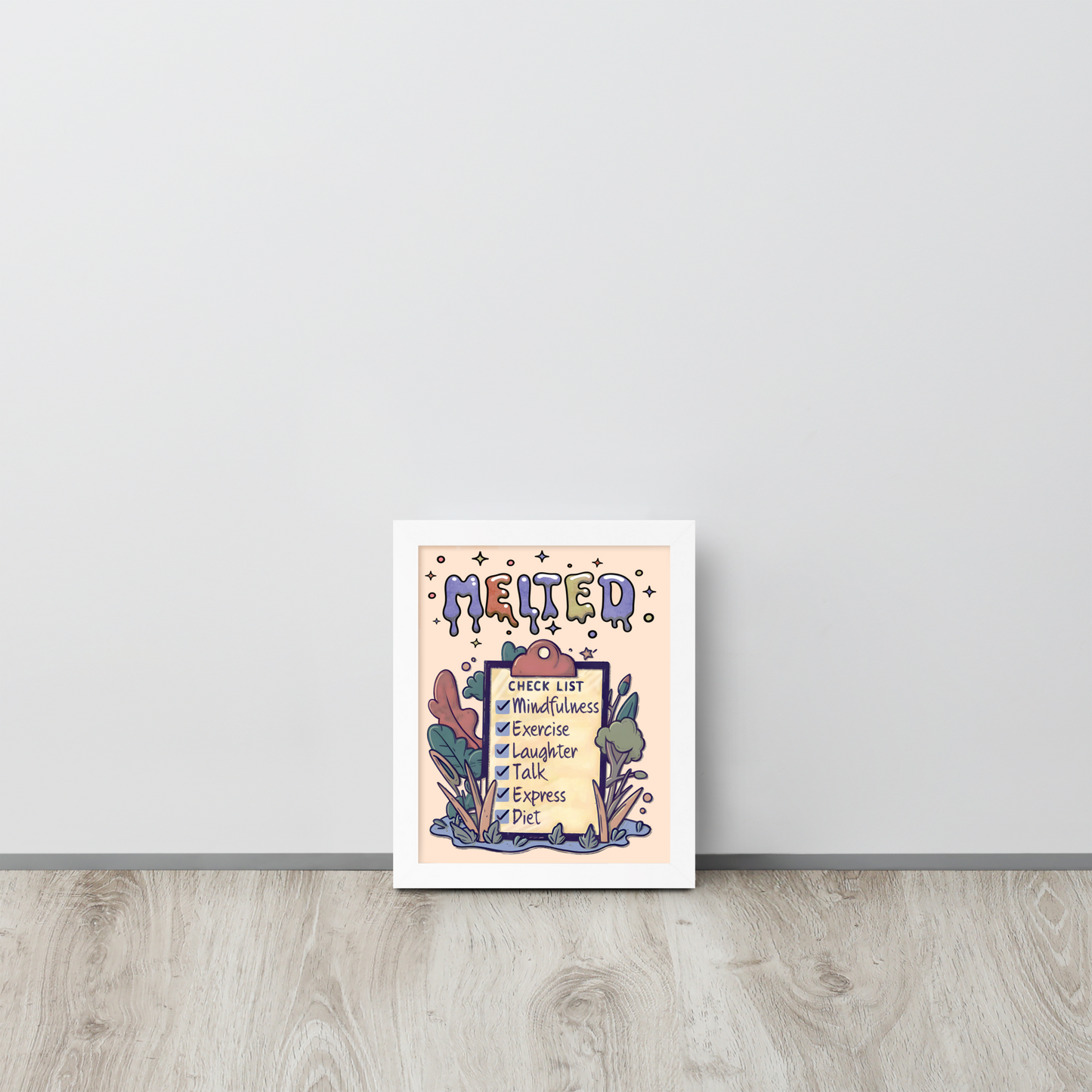 Framed illustrated poster with a white frame titled 'MELTED' featuring a checklist with items: Mindfulness, Exercise, Laughter, Talk, Express, Diet. The background includes whimsical abstract shapes and plants, and the poster is leaning against a white wall on a wooden floor.