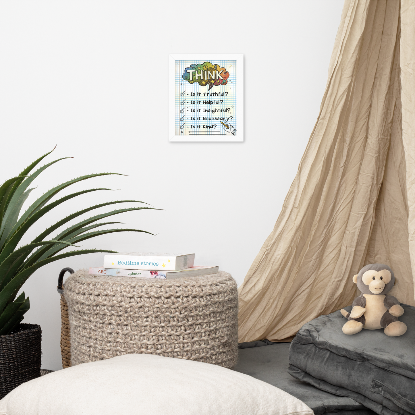 Framed illustrated poster with a white frame titled 'THINK' featuring a checklist with items: Is it Truthful?, Is it Helpful?, Is it Insightful?, Is it Necessary?, Is it Kind?. The poster hangs on a white wall above a cosy nook with a knitted pouffe, books, a plant, and a plush monkey toy.